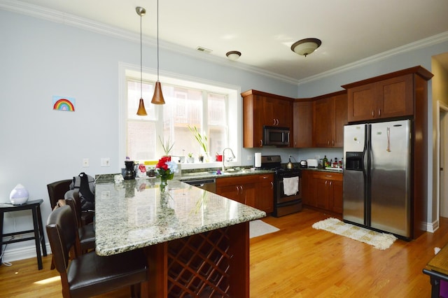 kitchen featuring stainless steel appliances, hanging light fixtures, light wood-type flooring, and kitchen peninsula