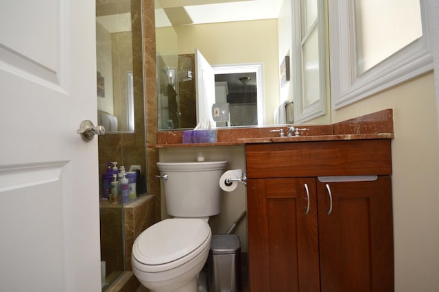 bathroom with a tile shower, vanity, and toilet