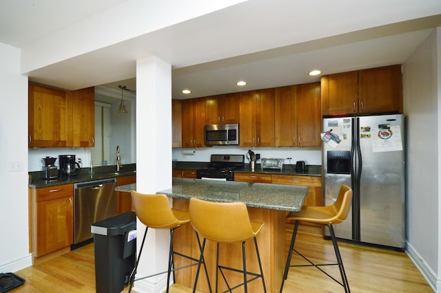 kitchen featuring sink, light hardwood / wood-style flooring, stainless steel appliances, a kitchen breakfast bar, and a kitchen island