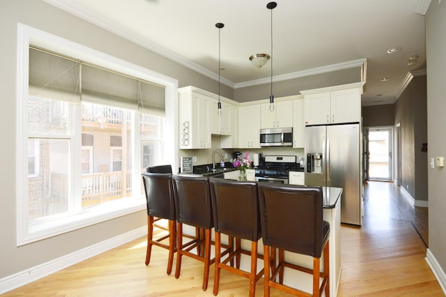 kitchen featuring stainless steel appliances, sink, pendant lighting, and white cabinets