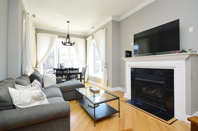 living room with a notable chandelier, crown molding, a fireplace, and light hardwood / wood-style floors