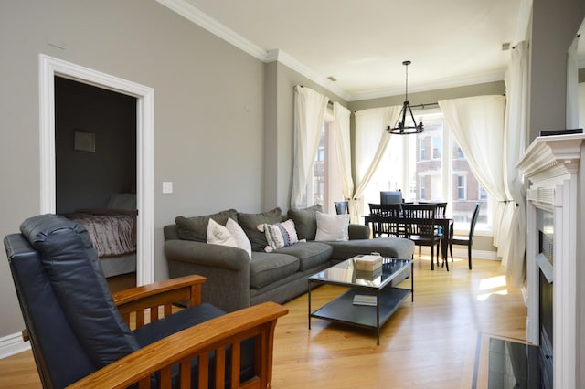 living room featuring ornamental molding, a notable chandelier, and light hardwood / wood-style flooring