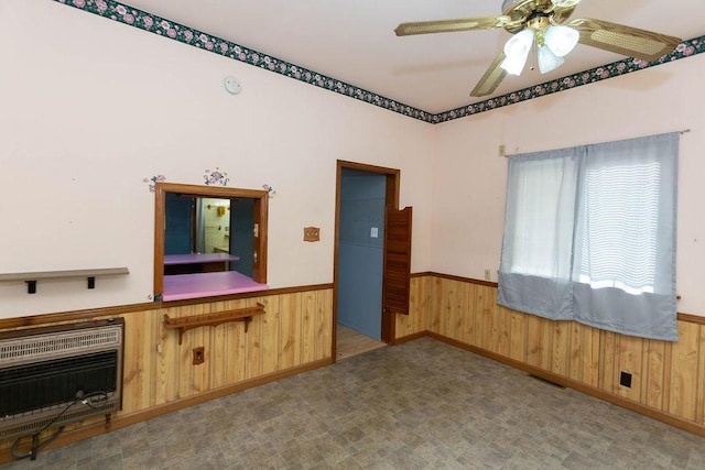 interior space featuring heating unit, ceiling fan, and wood walls