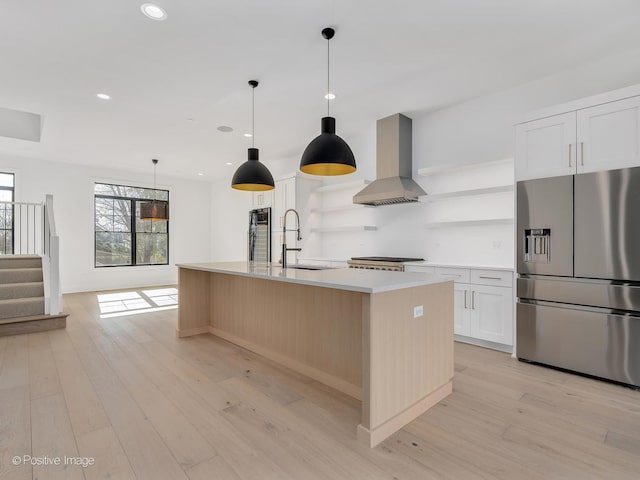 kitchen featuring sink, stainless steel fridge, white cabinetry, a spacious island, and island range hood