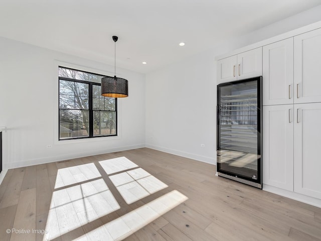 unfurnished dining area featuring beverage cooler and light hardwood / wood-style floors