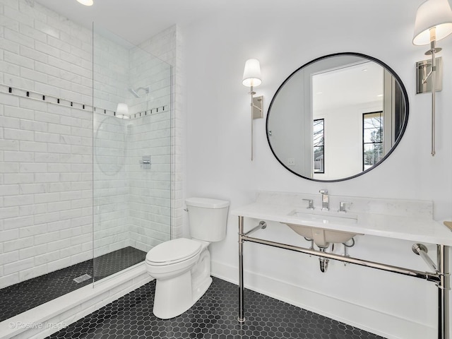 bathroom with tile patterned flooring, sink, toilet, and a tile shower