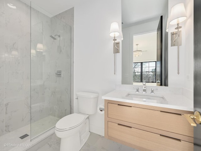 bathroom with vanity, tiled shower, and toilet