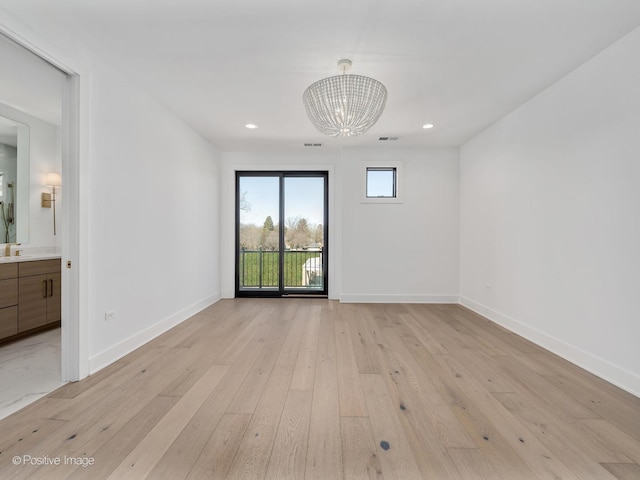 unfurnished room featuring light hardwood / wood-style flooring and a notable chandelier