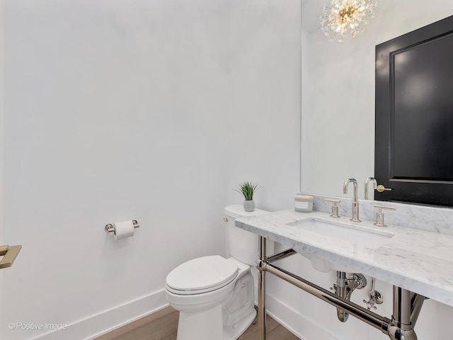 bathroom featuring an inviting chandelier, sink, wood-type flooring, and toilet