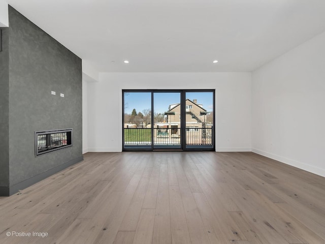 unfurnished living room with a large fireplace and light hardwood / wood-style floors