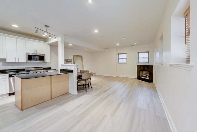 kitchen featuring a kitchen island, stainless steel appliances, white cabinets, and light wood-type flooring