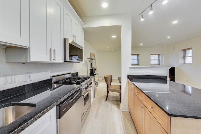 kitchen featuring white cabinetry, sink, dark stone countertops, stainless steel appliances, and light brown cabinets