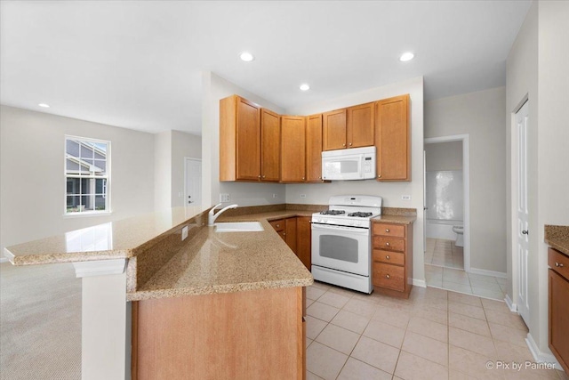 kitchen featuring light tile patterned flooring, sink, light stone counters, kitchen peninsula, and white appliances