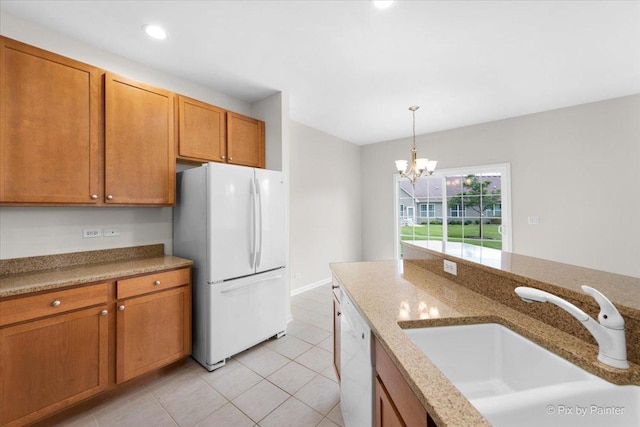 kitchen featuring sink, light stone counters, decorative light fixtures, light tile patterned floors, and white appliances