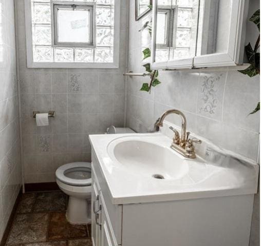 bathroom with vanity, tile walls, and toilet