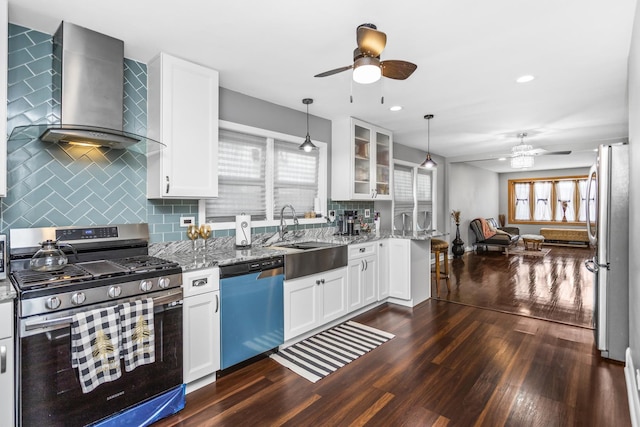 kitchen featuring sink, white cabinets, light stone counters, stainless steel appliances, and wall chimney range hood