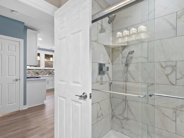 bathroom with a shower with door, hardwood / wood-style floors, and backsplash