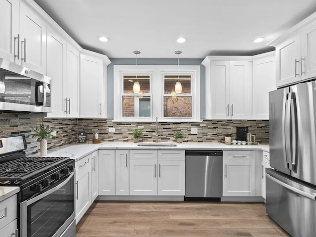 kitchen featuring sink, decorative light fixtures, white cabinets, and appliances with stainless steel finishes