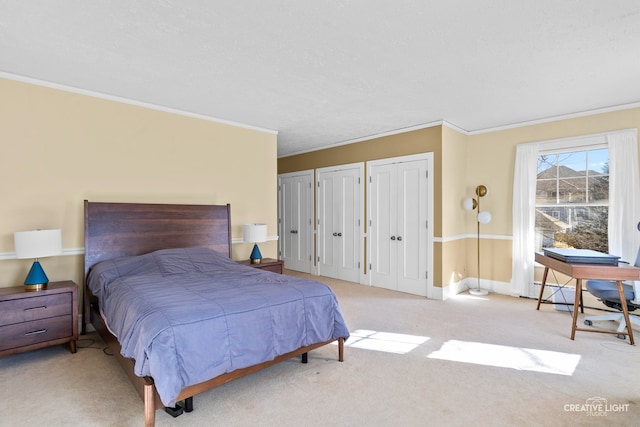 carpeted bedroom with crown molding and two closets