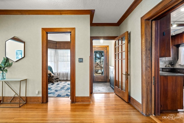 doorway featuring crown molding, a textured ceiling, and light wood-type flooring