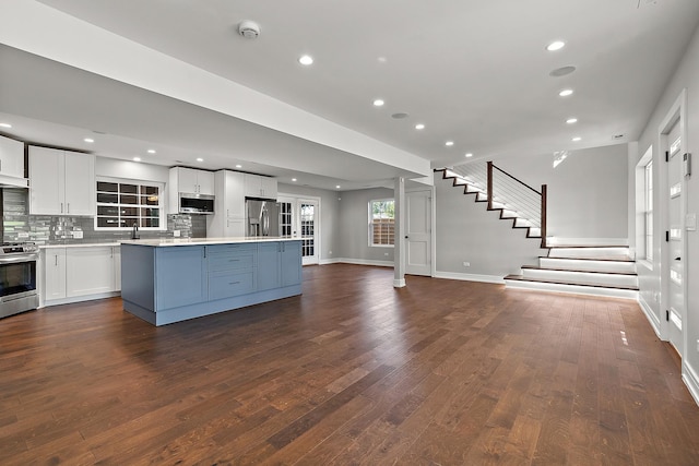 kitchen featuring a center island, appliances with stainless steel finishes, hardwood / wood-style floors, decorative backsplash, and white cabinets