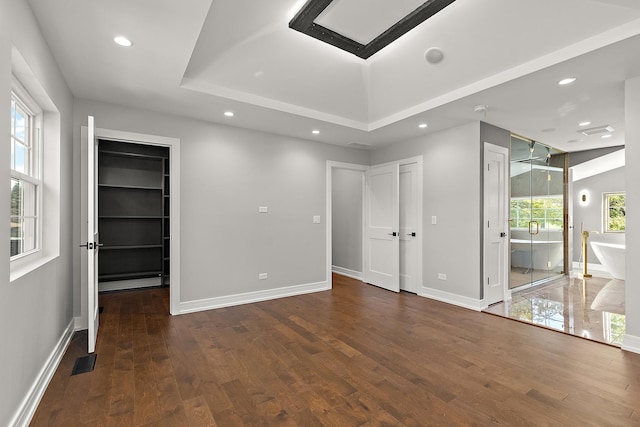 empty room with dark hardwood / wood-style flooring and a raised ceiling