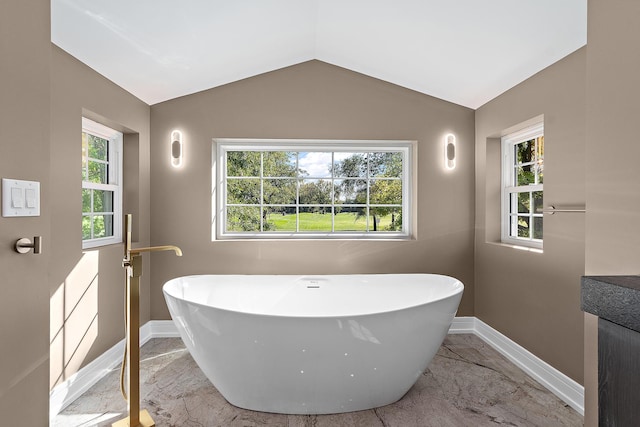 bathroom with plenty of natural light, lofted ceiling, and a bathtub