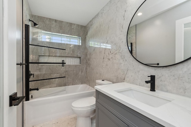 full bathroom with vanity, toilet, tiled shower / bath combo, and tile walls