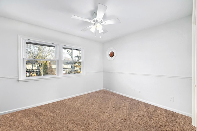 carpeted spare room with ceiling fan and baseboards