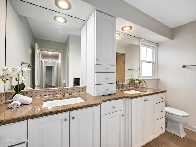 full bathroom featuring double vanity, a sink, toilet, and tile patterned floors