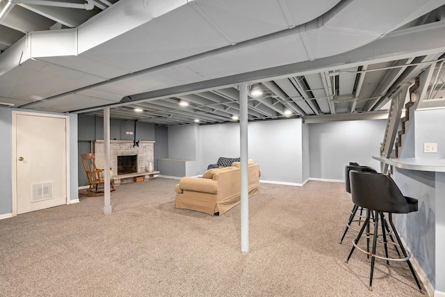 finished below grade area featuring carpet floors, visible vents, a fireplace with raised hearth, and baseboards