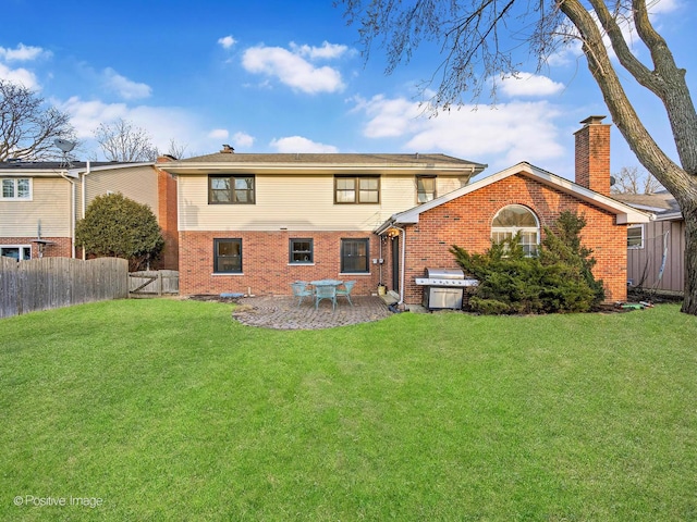 rear view of property featuring brick siding, a yard, a chimney, a patio, and fence