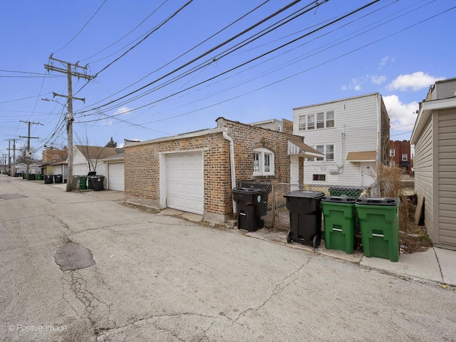 exterior space with a garage, an outdoor structure, and brick siding