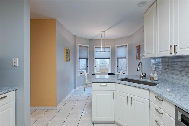 kitchen featuring sink, light tile patterned floors, dishwasher, white cabinets, and decorative light fixtures