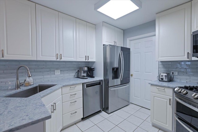 kitchen with light tile patterned flooring, sink, appliances with stainless steel finishes, decorative backsplash, and white cabinets