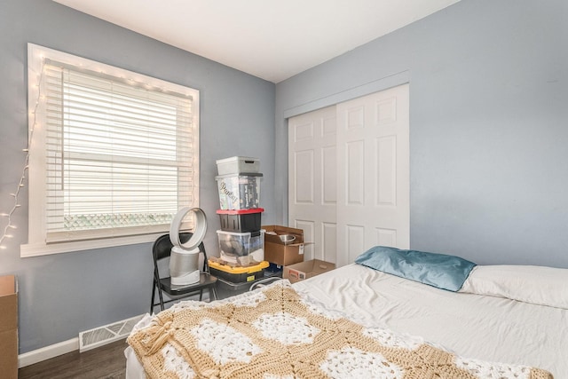 bedroom with dark hardwood / wood-style floors and a closet