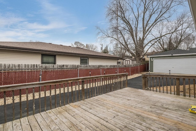 wooden terrace featuring a garage and an outbuilding