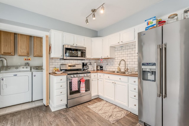 kitchen featuring sink, washer and dryer, white cabinets, and appliances with stainless steel finishes