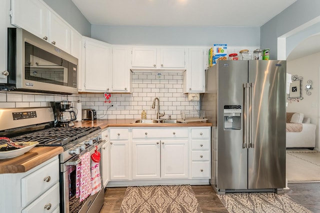 kitchen featuring butcher block counters, stainless steel appliances, and white cabinets