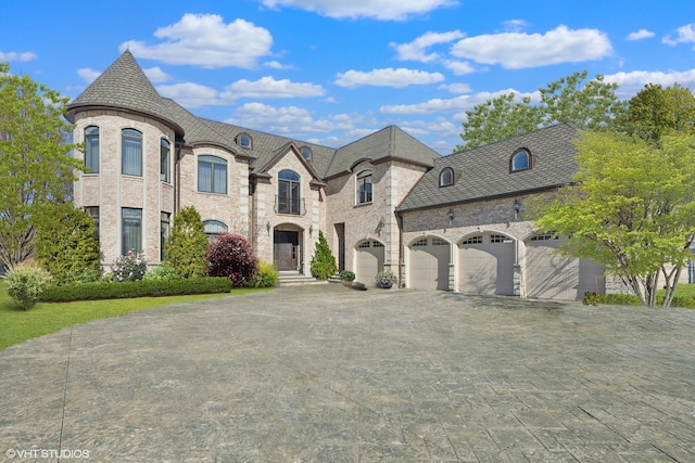 french provincial home featuring brick siding, decorative driveway, and an attached garage