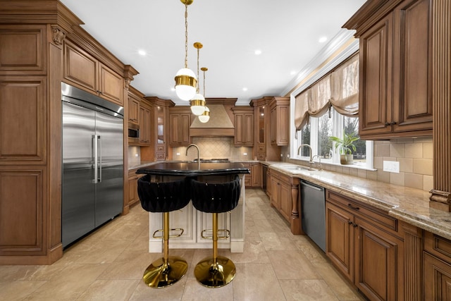 kitchen with tasteful backsplash, brown cabinets, built in appliances, custom exhaust hood, and a sink