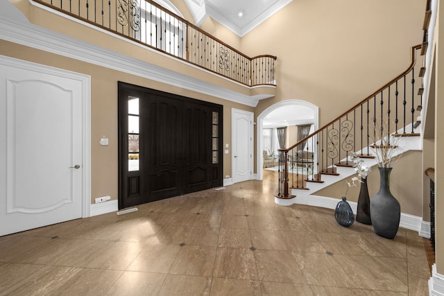 entryway with stairway, baseboards, arched walkways, and crown molding