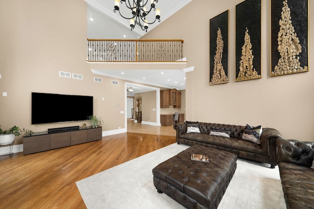 living room featuring a notable chandelier, crown molding, visible vents, and wood finished floors