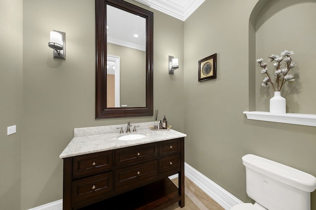 bathroom with toilet, crown molding, vanity, and baseboards