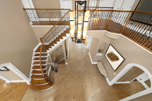 staircase featuring a high ceiling, tile patterned floors, and baseboards