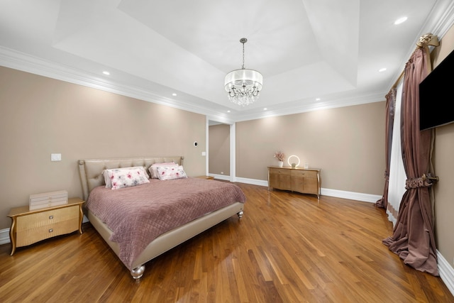 bedroom featuring light wood-style floors, a raised ceiling, crown molding, and baseboards