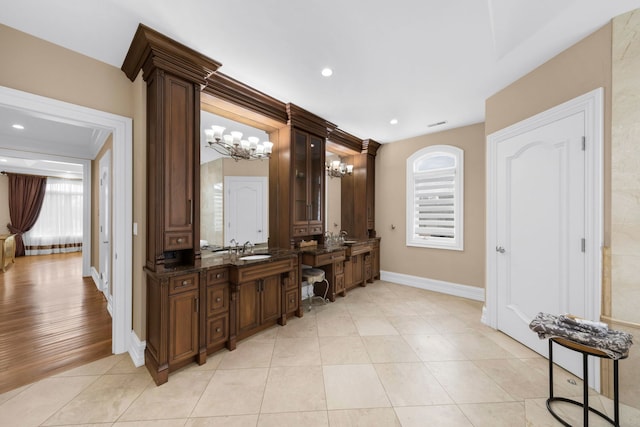 bar featuring light tile patterned floors, recessed lighting, an inviting chandelier, a sink, and baseboards