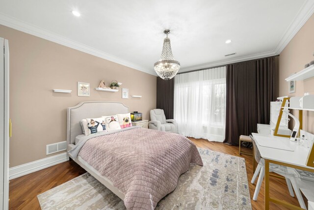 bedroom with ornamental molding, visible vents, baseboards, and wood finished floors