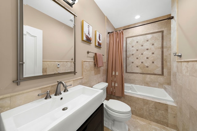 bathroom featuring tiled shower / bath combo, tile walls, toilet, and vanity