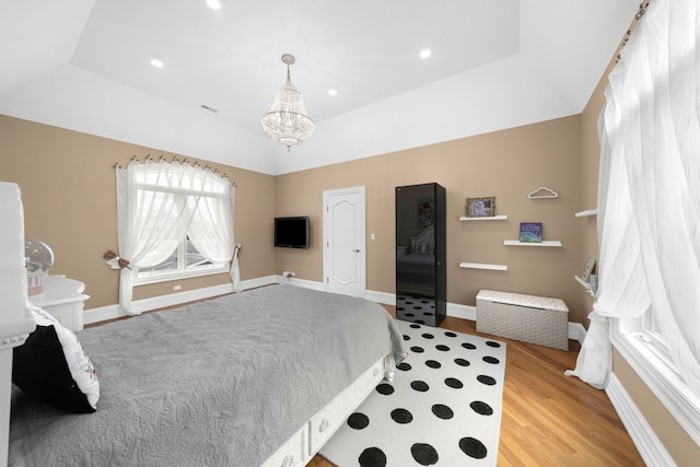 bedroom featuring a chandelier, a tray ceiling, baseboards, and light wood finished floors